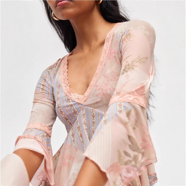 Ladies sheer mesh top with V-neck, lace trim, asymmetric ruffle hem, and bell sleeves Mune Fashion
