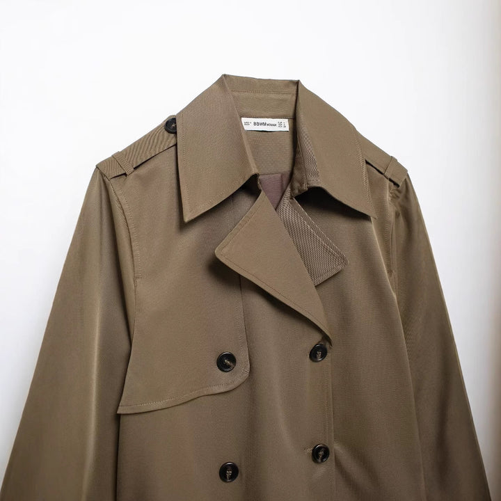 Women's short cropped trench coat in boxy cut with double-breasted button placket, shoulder epaulets and adjustable sleeve straps Mune Fashion
