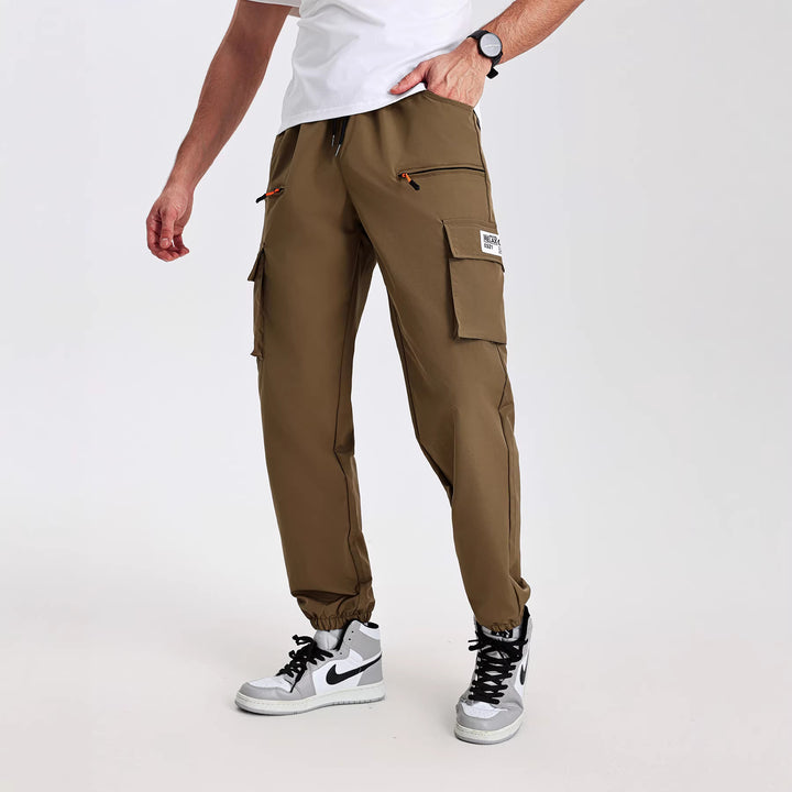 Men's tapered cut utility cargo pants in jogger style with drawstring waistband, zippered pockets & elastic leg cuffs Mune Fashion