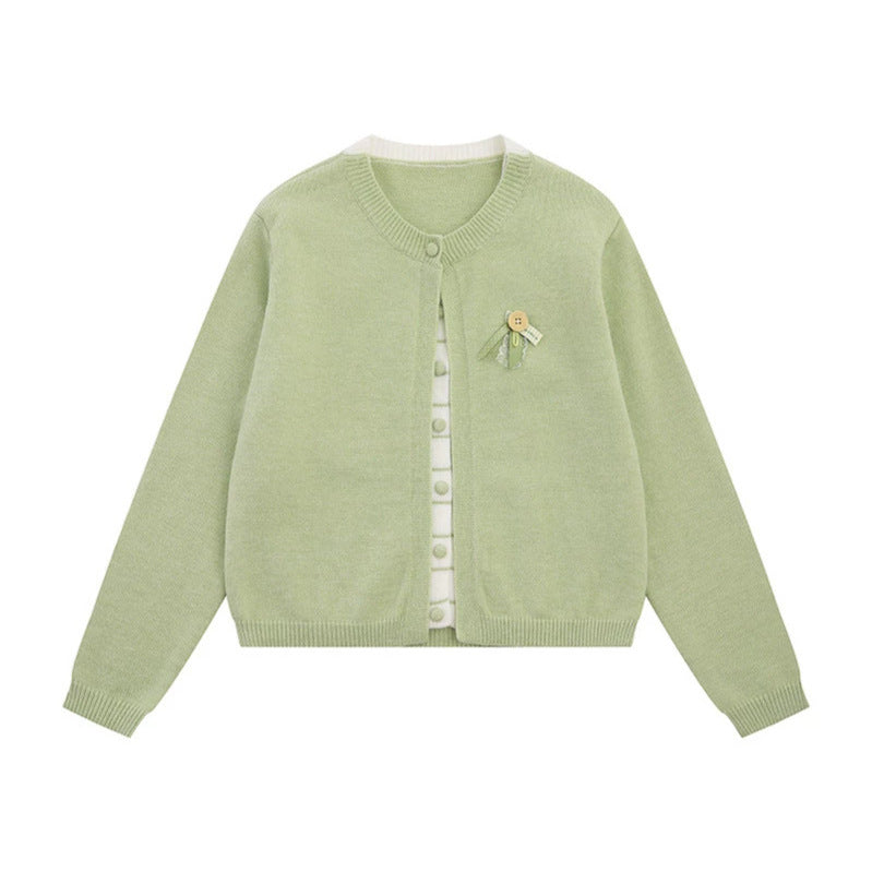 Ladies fine knit cardigan with round neckline, concealed button placket, and decorative brooch Mune Fashion