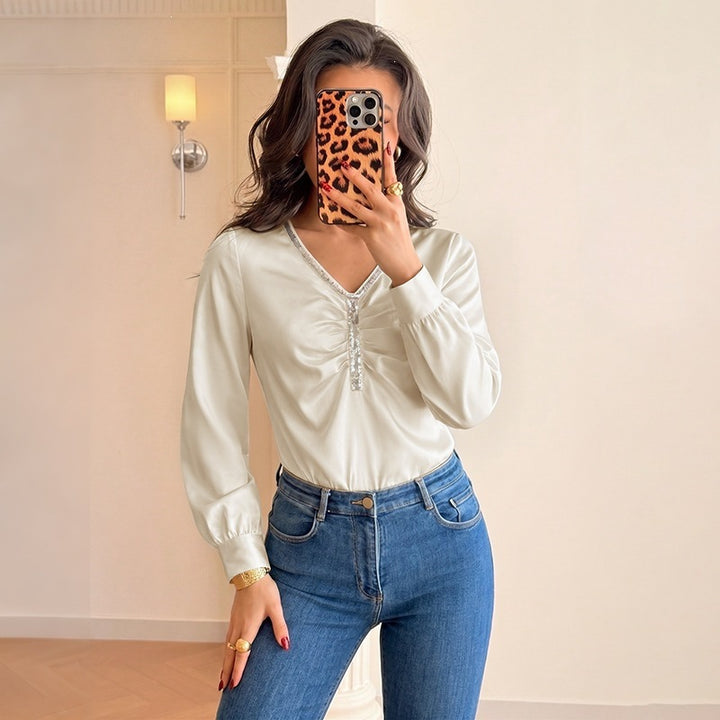 Women's satin blouse with V-neck, gathered front section and decorative ribbon.