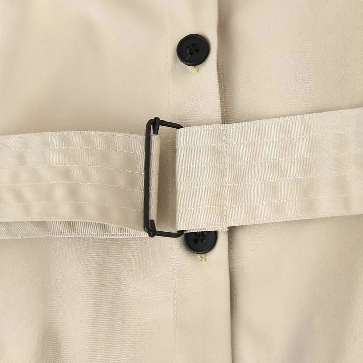 Women's longer tailored trench coat with waist belt, shoulder epaulettes, and continuous button placket Mune Fashion