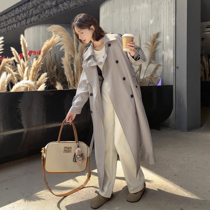Women's long-cut pinstripe trench coat with voluminous sleeves, shoulder epaulettes, and tie belt Mune Fashion