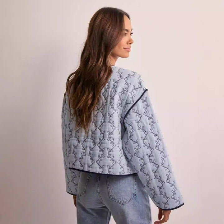 Women's quilted short jacket with V-neck, contrast piping, and floral quilted application Mune Fashion