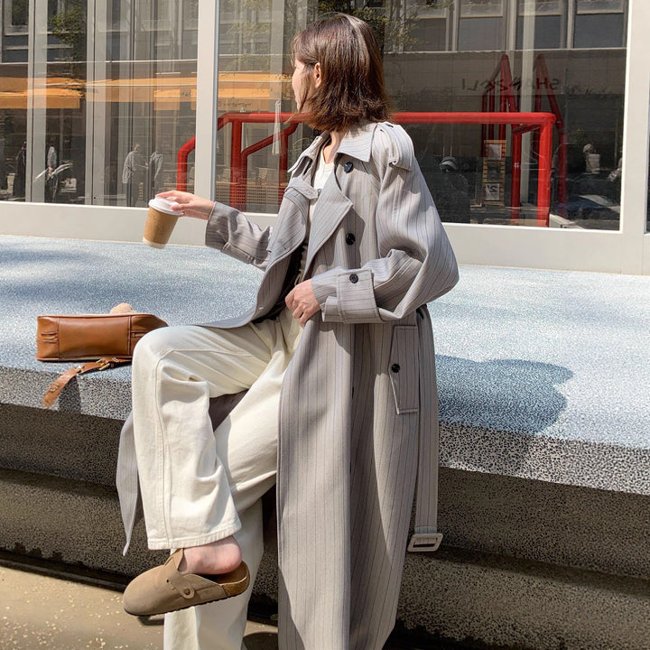 Women's long-cut pinstripe trench coat with voluminous sleeves, shoulder epaulettes, and tie belt Mune Fashion