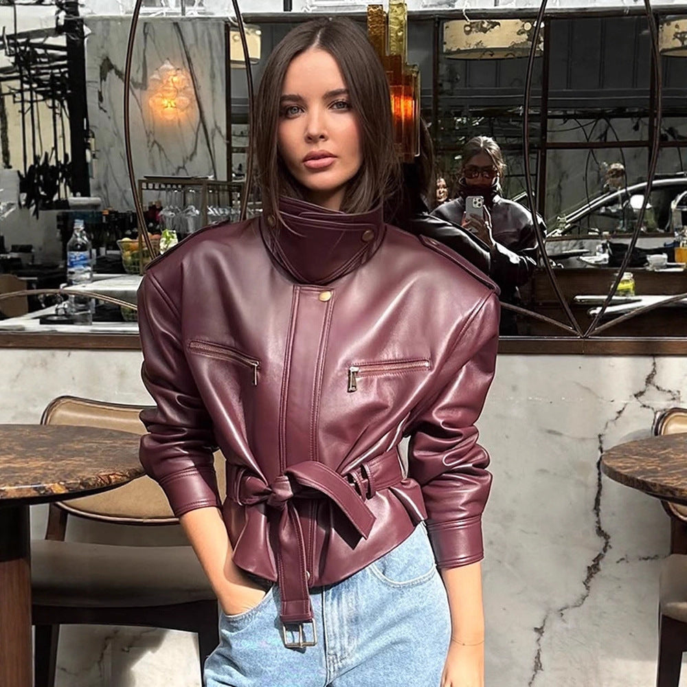 Women's short jacket made of faux leather with a high stand-up collar, fitted tie belt, and prominent shoulder pads Mune Fashion