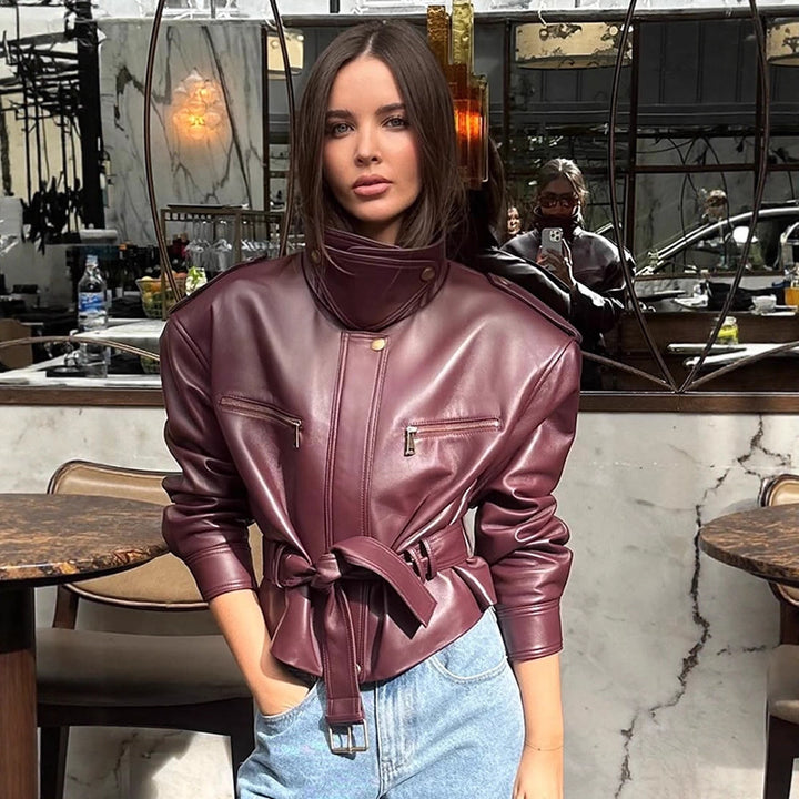 Women's short jacket made of faux leather with a high stand-up collar, fitted tie belt, and prominent shoulder pads Mune Fashion