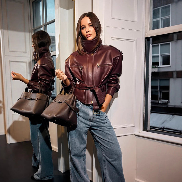 Women's short jacket made of faux leather with a high stand-up collar, fitted tie belt, and prominent shoulder pads Mune Fashion