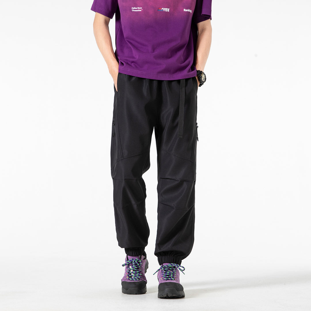 Men's loose technical cargo jogger pants with elastic drawstring waistband, patch flap pockets, and zippered leg pocket Drune