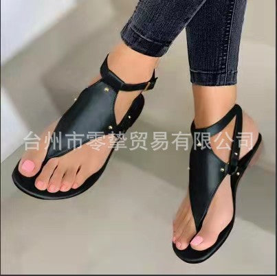 Women’s flat T-strap thong sandals with adjustable ankle strap and decorative floral appliqué in faux leather Mune Fashion