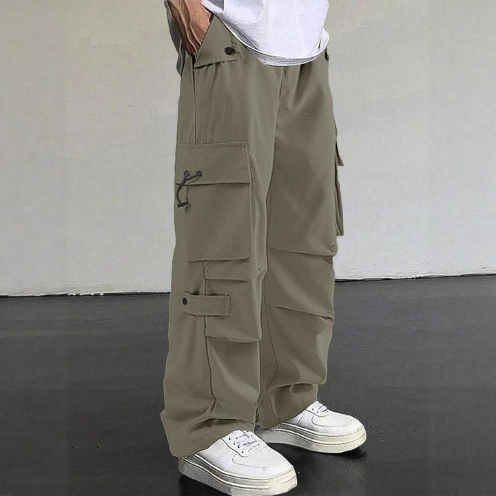 Men's baggy cargo pants with utilitarian flap pockets, drawstring waistband, and reinforced seams Mune Fashion