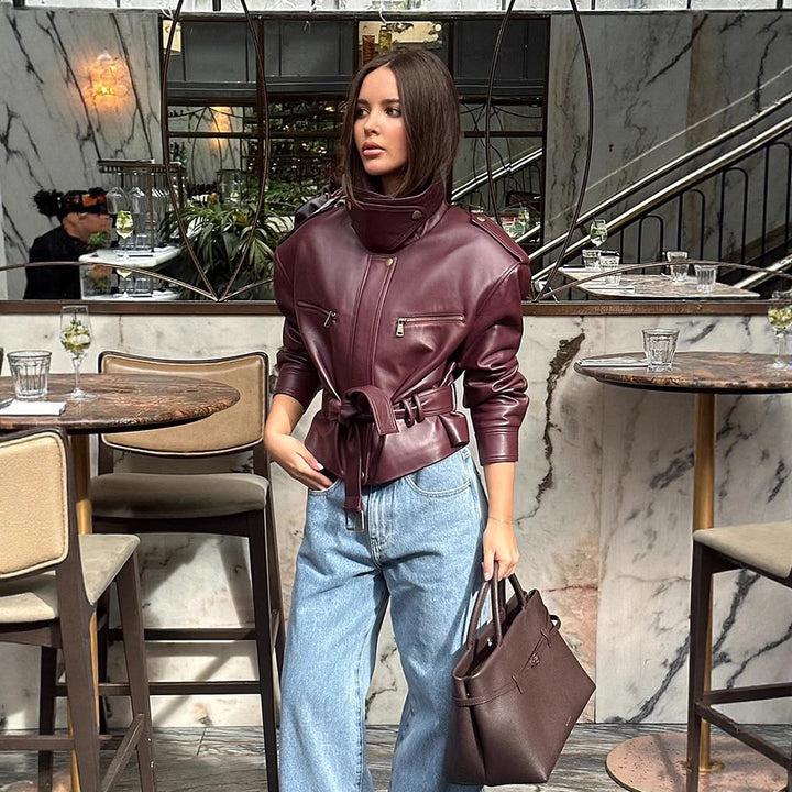 Women's short jacket made of faux leather with a high stand-up collar, fitted tie belt, and prominent shoulder pads Mune Fashion