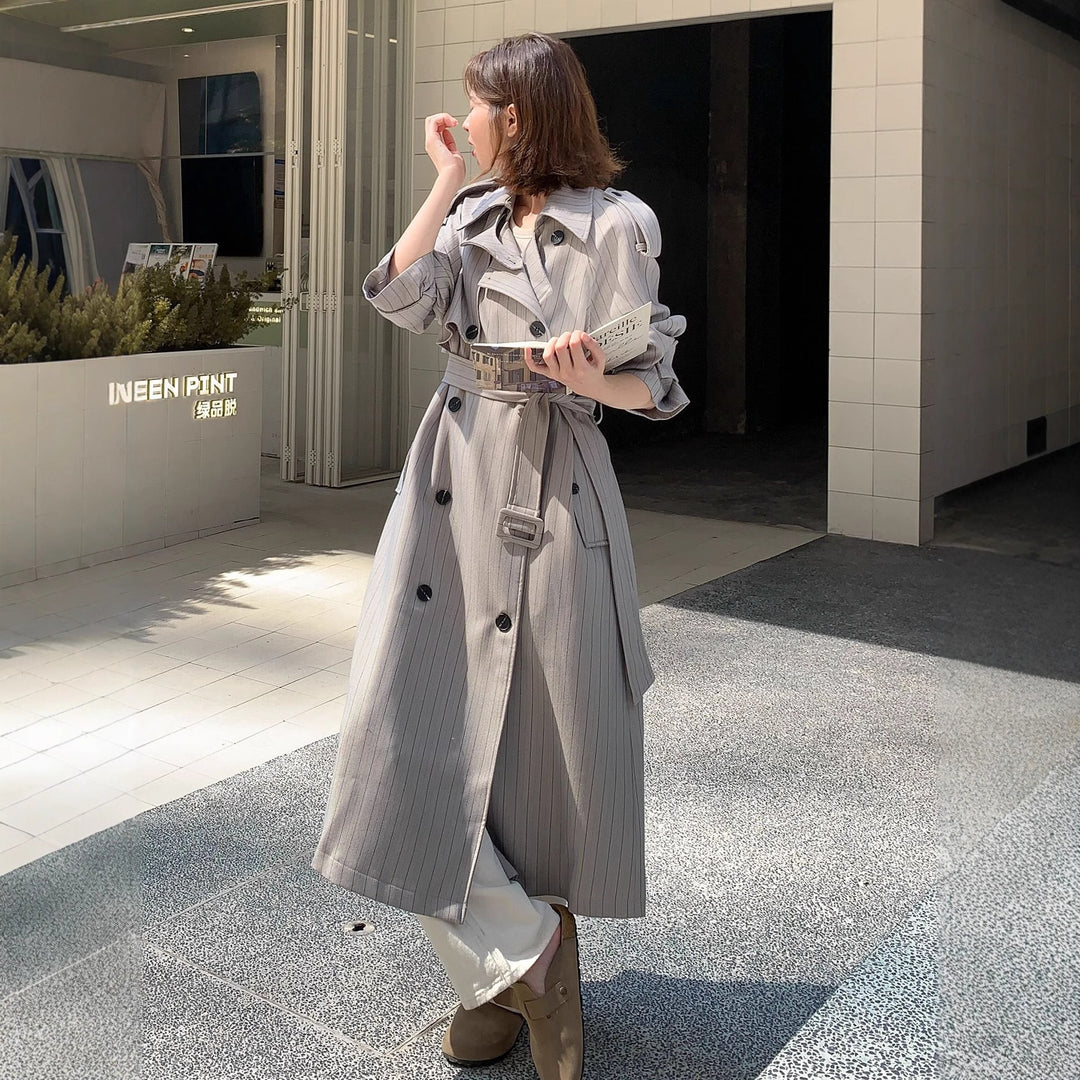 Women's long-cut pinstripe trench coat with voluminous sleeves, shoulder epaulettes, and tie belt Mune Fashion