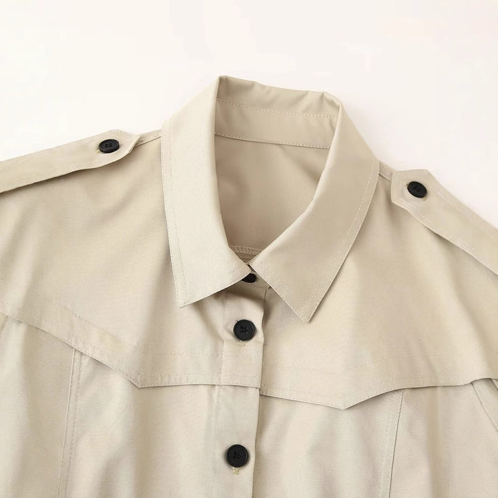 Women's longer tailored trench coat with waist belt, shoulder epaulettes, and continuous button placket Mune Fashion