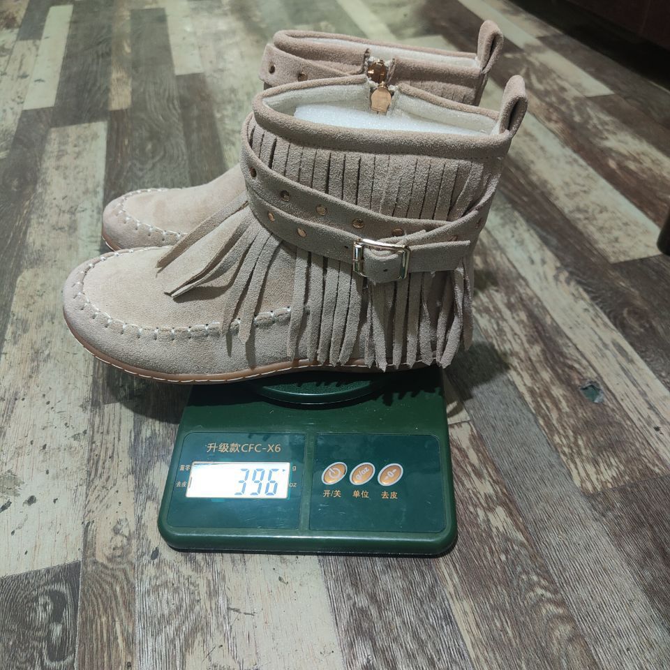 Women's fringe ankle boot in moccasin style with decorative studs, buckle strap, and side zipper Mune Fashion