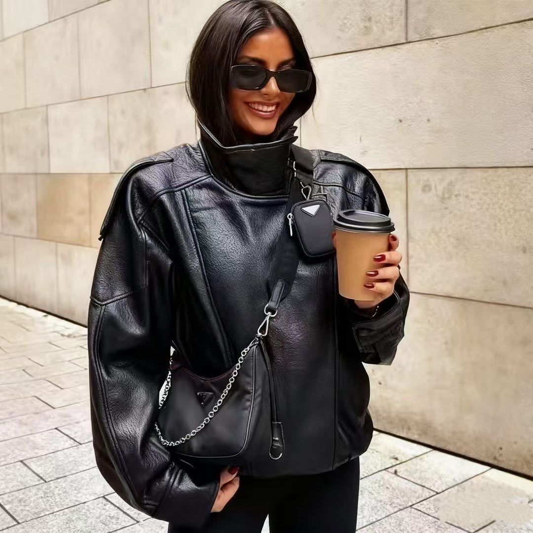 Women's oversized faux leather jacket with high standing collar, asymmetric button placket, shoulder flaps, and elastic hem Mune Fashion