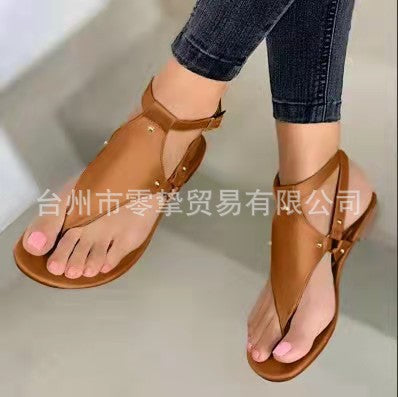 Women’s flat T-strap thong sandals with adjustable ankle strap and decorative floral appliqué in faux leather Mune Fashion