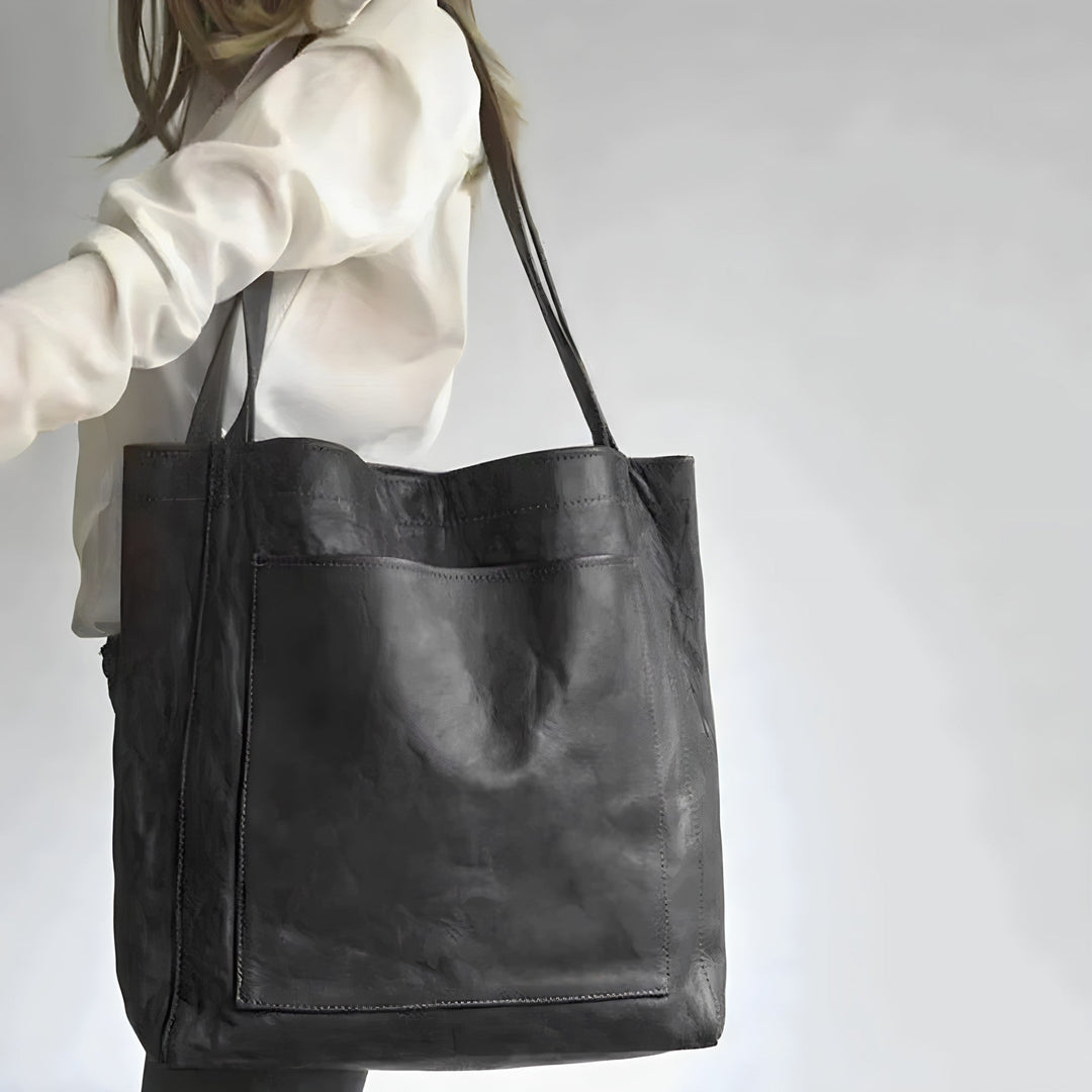 Frau trägt ein weißes Oberteil mit schwarzer Ledertasche